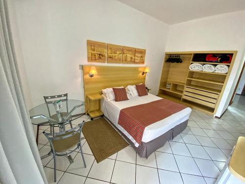 a bedroom with a bed and a glass table at Hotel Cabreúva Resort in Cabreúva