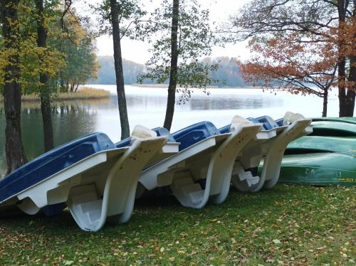 a row of empty boats on the grass near a lake at BALTĀ māja in Aglona