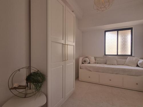 een witte slaapkamer met een bed en een raam bij Casa Dourada in Alvor