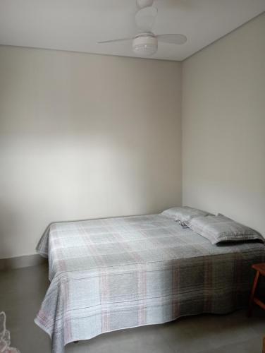 um quarto branco com uma cama com um cobertor xadrez em toledo casa completa em Americana