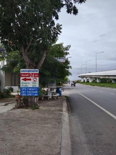 ein Schild an der Seite einer Straße mit einem Baum in der Unterkunft เพชรสุดาเฮ้าส์ in Phetchaburi