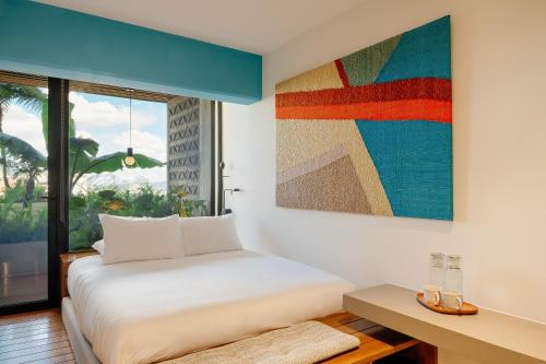 - une chambre avec un lit et une peinture murale dans l'établissement Good Hotel Guatemala City, à Guatemala