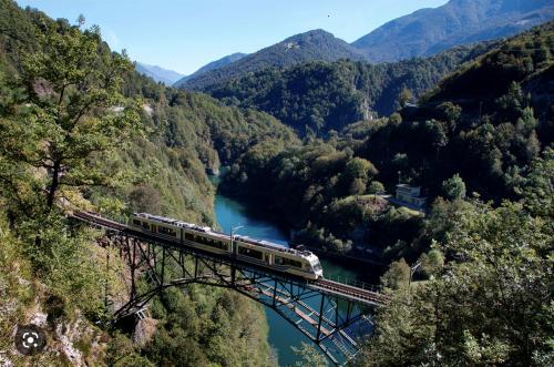 a train on a bridge over a river at Tolles Loft in den Tessiner Bergen in Corcapolo