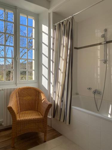 a bathroom with a wicker chair and a bath tub at Chateau La Rochette in Lisle