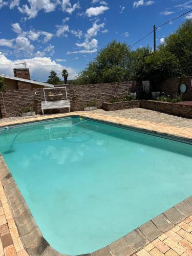 a large blue swimming pool with a bench in a yard at Ataria Place in Cradock