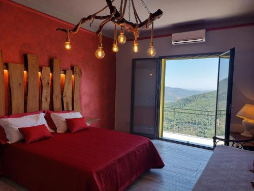 a bedroom with a red bed and a large window at IL NIDO TRA GLI ULIVI in Lucinasco
