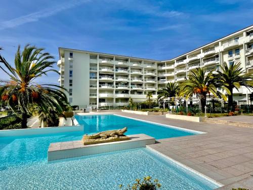 a swimming pool in front of a large building at Appartement tout confort vue mer in Antibes