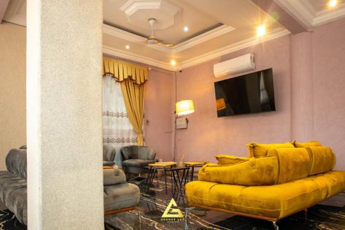 uma sala de estar com um sofá amarelo e uma televisão em GEORGE VEE HOTEL LTD em Kumasi