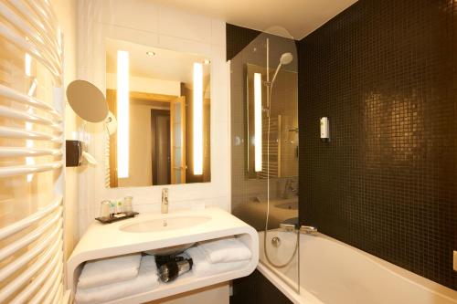 La salle de bains est pourvue d'un lavabo, d'une douche et d'une baignoire. dans l'établissement Best Western Plus Hôtel Le Rhénan & Restaurant Chez Claude, à Dorlisheim