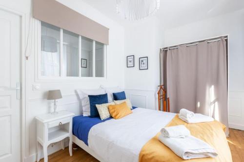 Dormitorio blanco con cama con almohadas azules y naranjas en L'Escale - de Disney à Paris - Cocon Hyper Centre, en Lagny