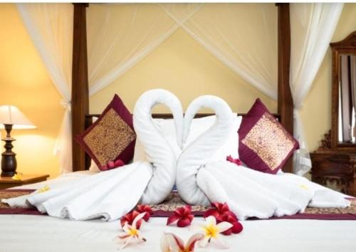 Una cama con dos cisnes hechos de toallas. en Buana Ubud Inn, en Ubud