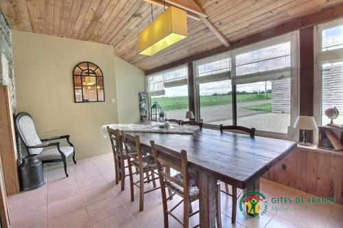 une salle à manger avec une grande table et des chaises en bois dans l'établissement Chambres d'hôtes - Au Domaine des Camélias, à Pluméliau