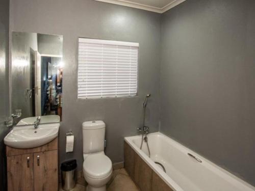 a bathroom with a toilet and a sink and a tub at Dew Drop Inn in Nelspruit