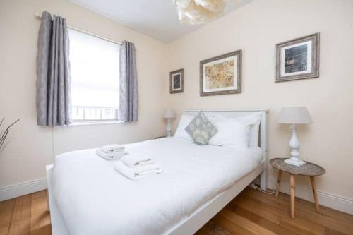 a white bedroom with a large bed and a window at Artist's CENTRAL apartment! in Dublin