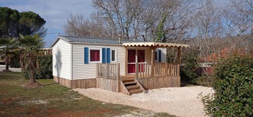 ein kleines Haus mit einer Veranda und einer Terrasse in der Unterkunft CAMPING LE BEL AIR mobil home LE FIGUIER 6 personnes in Limogne-en-Quercy