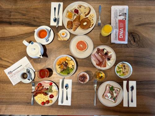 a wooden table topped with plates of breakfast food at Best Western Plus Hôtel Le Rhénan & Restaurant Chez Claude in Dorlisheim