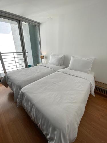 two white beds in a room with a large window at Aqua Loft in Quito