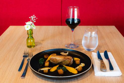 a table with a plate of food and a glass of wine at Best Western Plus Hôtel Le Rhénan & Restaurant Chez Claude in Dorlisheim
