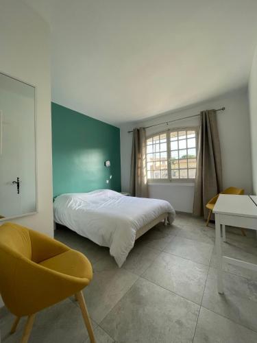 une chambre avec un lit, une chaise et une table dans l'établissement Villa Andrée avec piscine à proximité de la mer, à Saint-Cyr-sur-Mer