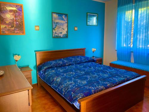 1 dormitorio con paredes azules y 1 cama con sábanas azules en La casa delle janas, en Platamona