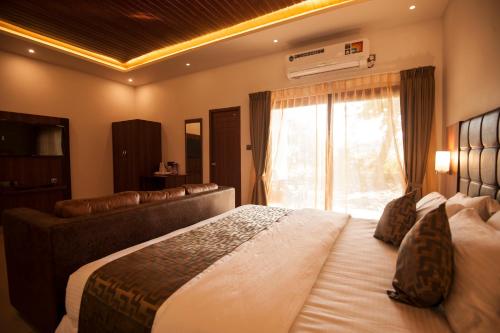 a bedroom with a large bed and a large window at MC Resort Wildlife Resort Bandipur in Bandipūr