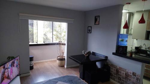 ein Wohnzimmer mit einem Tisch und einem Fenster in der Unterkunft Apartamento bom descanso in Serra Negra