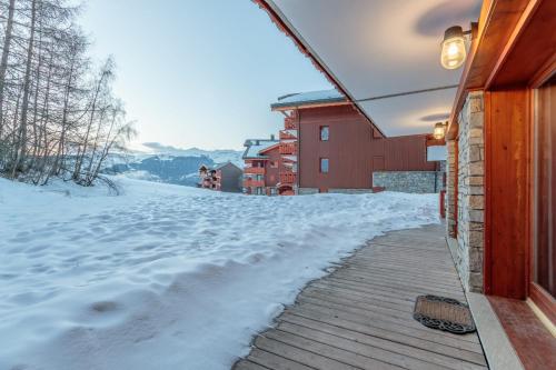 une terrasse couverte couverte de neige d'une maison avec une cour couverte de neige dans l'établissement Beautiful wooden chalet in La Plagne, à Aime La Plagne