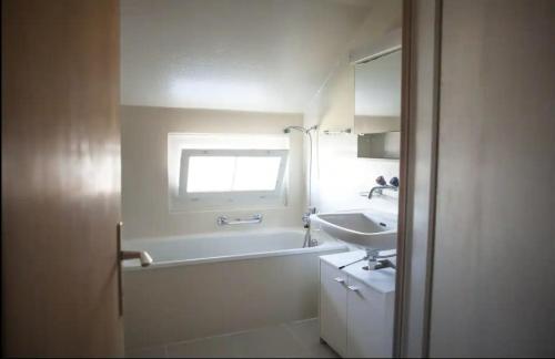 a bathroom with a bath tub and a sink at Lakeview Rustic in Krattigen