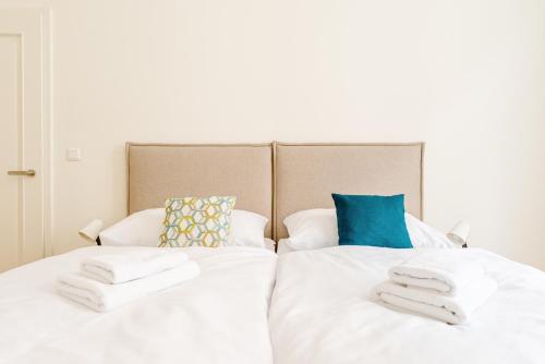 a bedroom with two beds with white sheets and blue pillows at Apartment Brno in Brno
