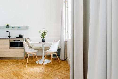 a white kitchen with a table and chairs at Apartment Brno in Brno