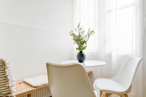 a white dining room with a table and white chairs at Apartment Brno in Brno