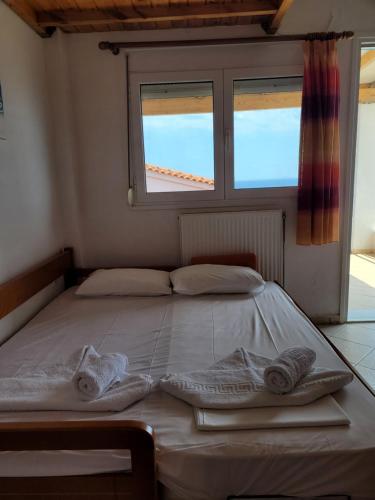 a bed with towels on it in a room with a window at LEFKADA TWINS 4 in Agios Kirykos