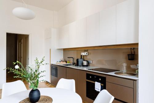 a kitchen with white cabinets and a table and chairs at Apartment Brno in Brno