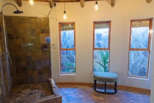 a bathroom with a shower and a chair and windows at Onjala in Eorondemba