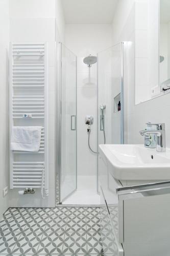 a white bathroom with a shower and a sink at Apartment Brno in Brno