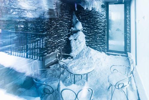a balcony covered in snow with tables and chairs at Hotel BEI SCHUMANN in Kirschau