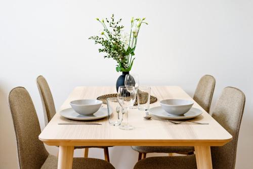 a wooden table with chairs and a vase with flowers at Apartment Brno in Brno