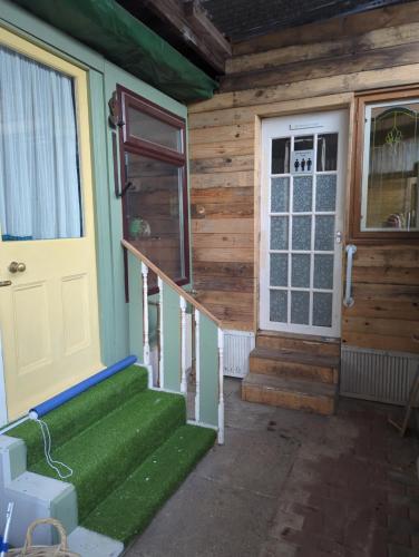 a front door of a wooden house with green stairs at The Old Hay Barn in Bursledon