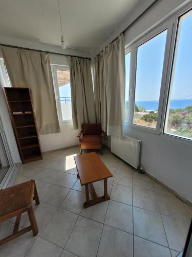 a living room with a table and chairs and windows at LEFKADA TWINS 1 in Agios Kirykos