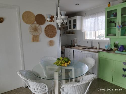 a kitchen with a glass table and white chairs at apartamento som do mar. in Fortaleza