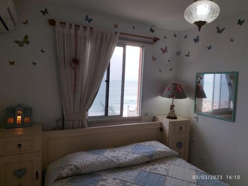 a bedroom with a bed and a window with butterflies on the wall at apartamento som do mar. in Fortaleza