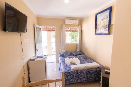 Habitación pequeña con cama y TV. en Pousada Três Praias en Guarapari