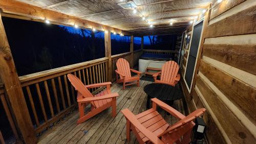 a porch with chairs and a table and a bed at Rustic Cabin in Sevierville