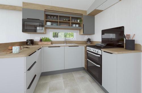 a kitchen with white cabinets and black appliances at The Telford Van - Beautiful, luxury static caravan in Aberlour