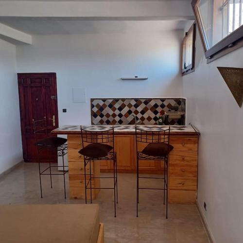 a kitchen with three bar stools and a counter at Balcon sur l'ocean in Taghazout