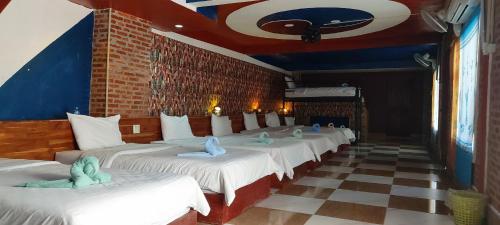 a row of white beds with stuffed animals on them at Mekong Backpackers in Pakbeng