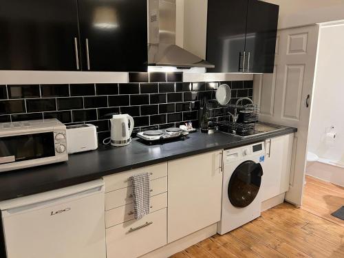 a kitchen with a washer and dryer and a microwave at Preston Room Let in Yeovil