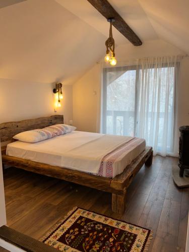 a bedroom with a large bed with a large window at Casa de vacanta traditionala La Fanar in Schiuleşti