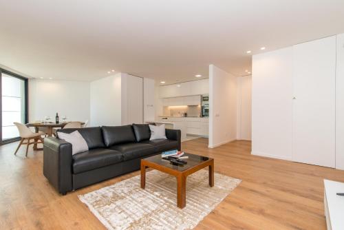 a living room with a black couch and a table at Luxo à Beira-Mar na Ria Formosa in Olhão