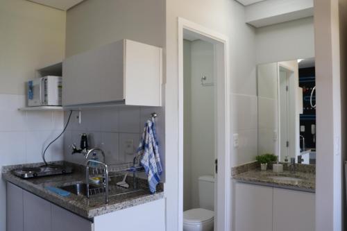 a white kitchen with a sink and a toilet at Flat com Wifi, Pisicina e Estacionamento in Ribeirão Preto